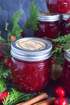 three jars filled with cranberry sauce surrounded by christmas greenery and cinnamon sticks