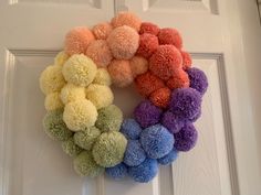 a multicolored pom - pom wreath hangs on the front door