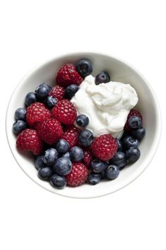 berries, yogurt and blueberries in a white bowl on a white background