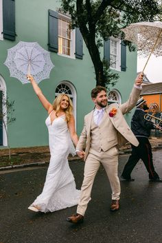 a bride and groom walking down the street holding umbrellas in their hands as they walk