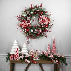 a christmas wreath is hanging on the wall above a table with candy canes and candies