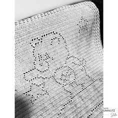 a white crocheted blanket with a teddy bear on the front and back side