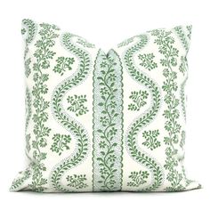 a green and white pillow with an intricate design on the front, sitting on a white surface