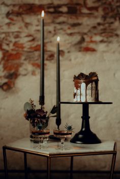 two candles are lit on a table with glasses