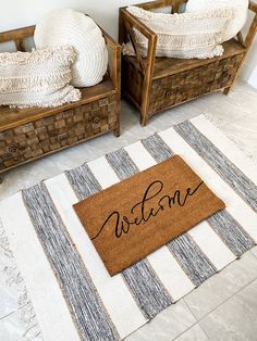 a welcome mat on the floor in front of two wooden benches with pillows and blankets