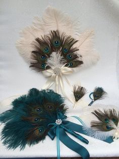 several peacock feathers and ribbons on a white cloth with blue satin ribbon tied around them