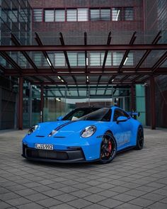 a blue sports car parked in front of a building