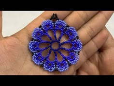 a hand holding a blue beaded brooch