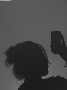 black and white photograph of a woman taking a photo with her cell phone in the dark