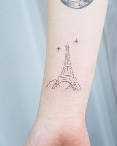 a small wrist tattoo with the eiffel tower on it's left arm