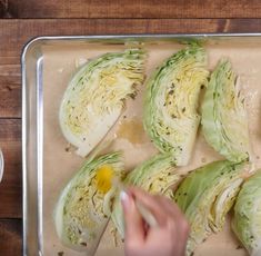 someone is peeling an artichoke in half on a baking sheet with butter and seasoning