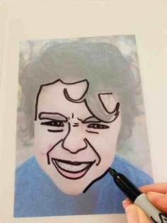 a person is drawing a face on a piece of paper