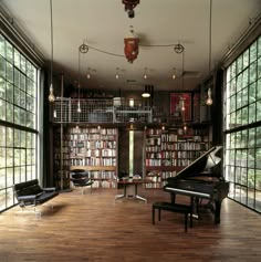 a large room with lots of windows and a piano in the center, surrounded by bookshelves