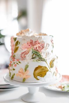 a white cake decorated with flowers and leaves