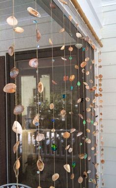 a close up of a window with shells hanging from it's glass rods and beads