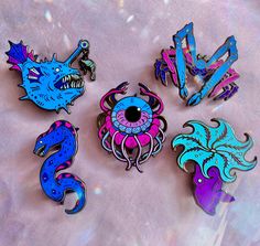 five different colored brooches with designs on them