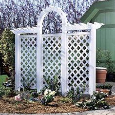 a white trellis with potted plants in the foreground