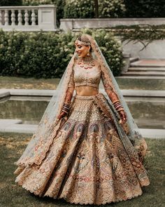 a woman in a bridal gown standing on the grass with her hands behind her head