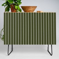 a potted plant sitting on top of a wooden table next to a green cabinet