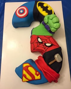 a birthday cake made to look like the number 3 with superman and spiderman on it