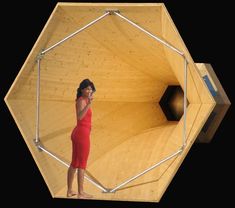 a woman standing in front of a wooden structure holding a cell phone to her ear