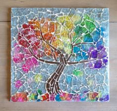 a colorful tree made out of glass on a wooden table with white and blue tiles