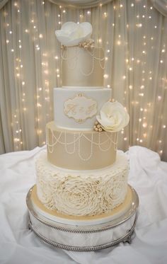 a three tiered wedding cake sitting on top of a white tablecloth covered table