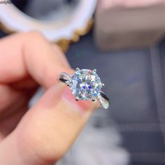 a person holding an engagement ring with a diamond in it's center and side stones on the band