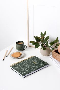 a white table topped with books and a cup of coffee next to an egg on a plate