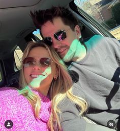 a man and woman sitting in the back seat of a car