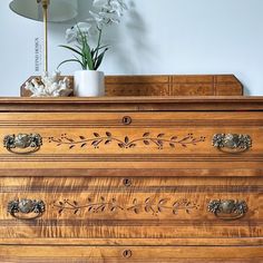 a wooden dresser with drawers and flowers on top