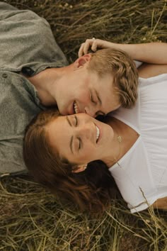 a man and woman laying on the ground together smiling at each other's eyes