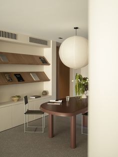 a table and chairs in a room with shelves on the wall behind it, and a lamp hanging from the ceiling