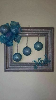 a frame with ornaments hanging on it and a blue bow attached to the front of it