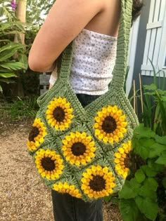 a woman is holding a crocheted bag with sunflowers on the front