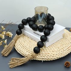 black beads and tassels are on top of a stack of books next to a candle