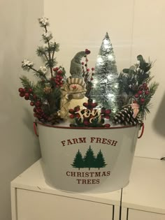 a white bucket filled with christmas trees and decorations