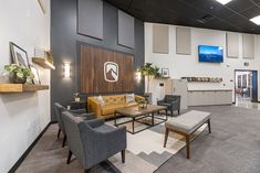 an office lobby with chairs, couches and tables in front of a wall mounted flat screen tv