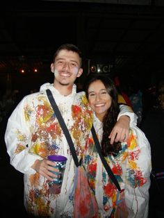 a man and woman standing next to each other in front of a building at night