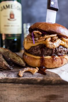 a cheeseburger on a wooden cutting board with a bottle of wine in the background