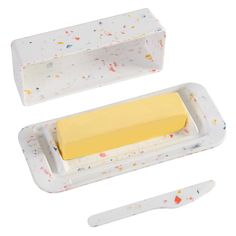 a butter knife and butter block in a white container with sprinkles on it