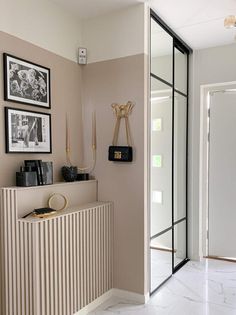 a white and beige hallway with pictures hanging on the wall next to a radiator