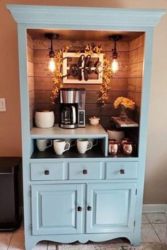 a blue hutch with coffee maker and cups on it's side, sitting in front of a brown wall