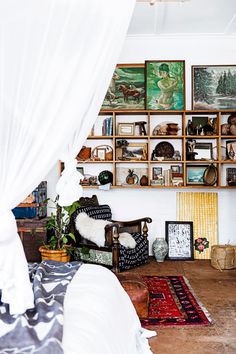 a bed sitting in a bedroom next to a wall filled with pictures and books on it