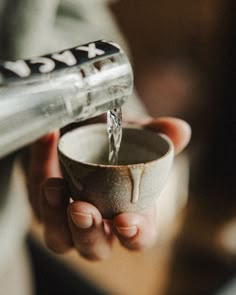 a person is pouring something into a cup with a metal spigot in it