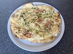 a pizza sitting on top of a white plate covered in cheese and meat toppings