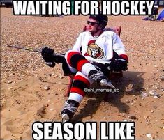 a man sitting on top of a sandy beach next to a sign that says waiting for hockey season like