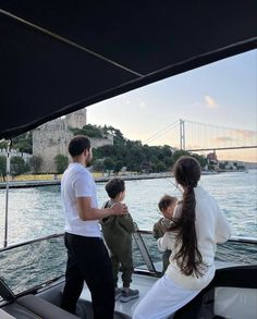 a man and two children on a boat in the water with a bridge in the background