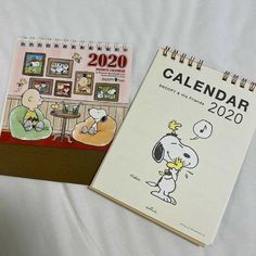 two calendars sitting on top of a bed next to each other with cartoon characters