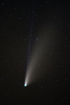 an image of a comet in the sky with stars around it and a bright green beam